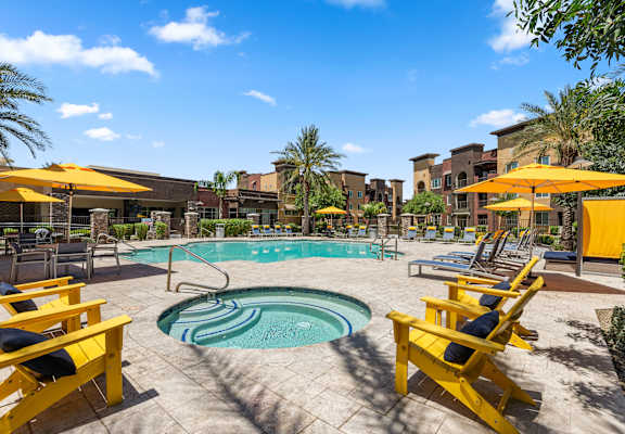 a swimming pool with yellow chairs and umbrellas at the resort